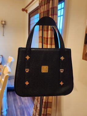 vintage MCM black studded leather top handle bag featuring gold-tone hardware. 